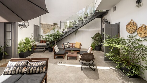 Um espaço de estar ao ar livre moderno com sofá, cadeiras, mesa de centro e escada.