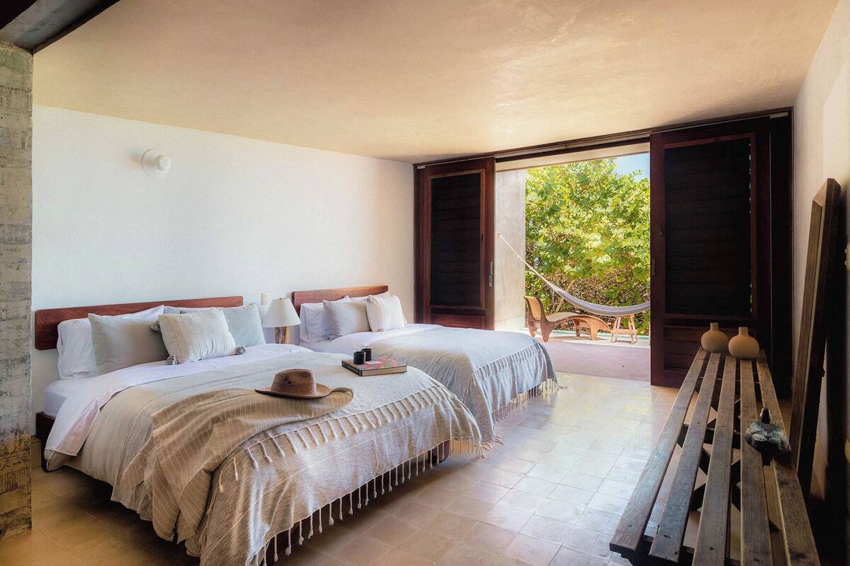 A room with two beds, a hammock, and a bench.