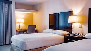 A hotel room with two beds, a desk, and a chair. There are lamps on the desk and bedside tables. - Studio Coliving (Panama City)