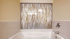A modern bathroom with a large bathtub, a wall-mounted faucet, and a decorative panel with vertical lines. - Studio Coliving (Panama City)