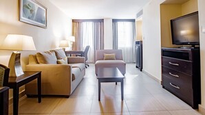 A hotel room with a sofa, a coffee table, a TV, and a cabinet. - Studio Coliving (Panama City)