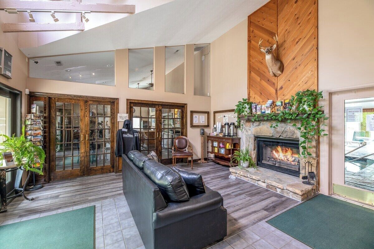 A spacious living area with a fireplace, leather sofa, and a deer mounted on the wall.