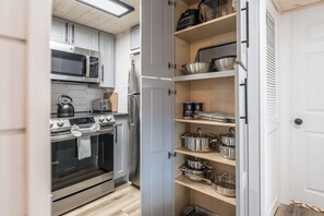 A kitchen with stainless steel appliances, a microwave, a kettle, and a built-in oven. There is a pantry with shelves holding pots and pans. - Mountain Views Indoor Pool Access Sauna Access (Gatlinburg)