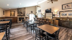 Un restaurant doté de nombreuses tables et chaises, d’une cheminée en pierre et d’un espace bar.