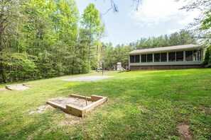 A backyard with a wooden deck, a basketball hoop, and a house with a large windowed porch. - Mountain Views Indoor Pool Access Sauna Access (Gatlinburg)