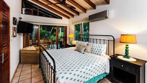 Un dormitorio con cama, mesita de noche, televisor y ventilador de techo.