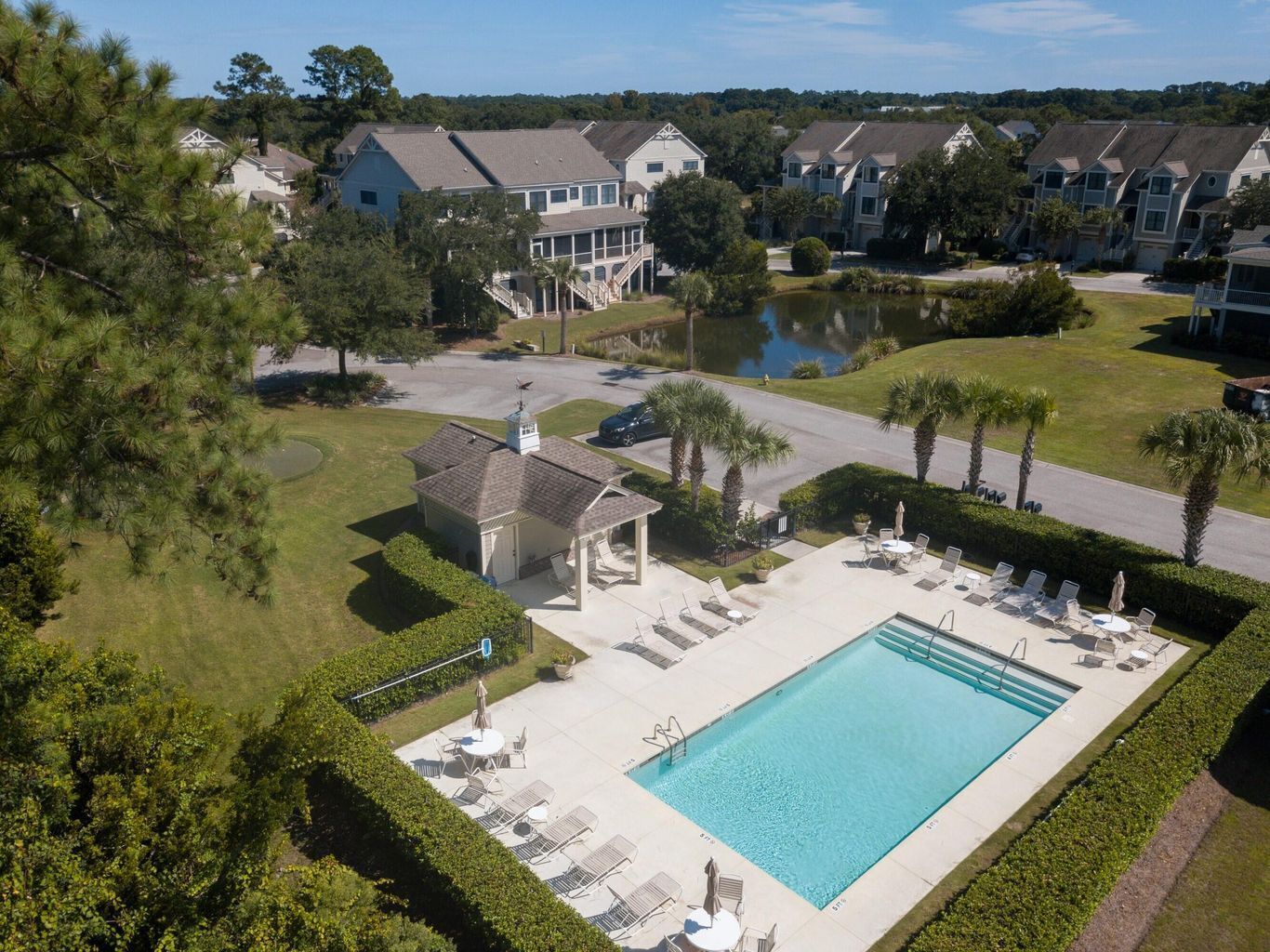 A residential area with a swimming pool, lounge chairs, and a small pavilion.