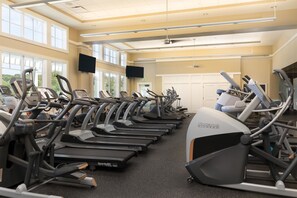 A gym with multiple treadmills and stationary bikes, large windows, and a clean, modern design.