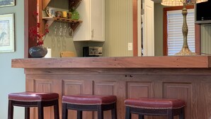 Una zona de bar con tres taburetes, una encimera y un espejo encima.