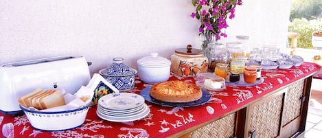 Une table de petit-déjeuner avec divers aliments, un grille-pain et des assiettes décoratives.
