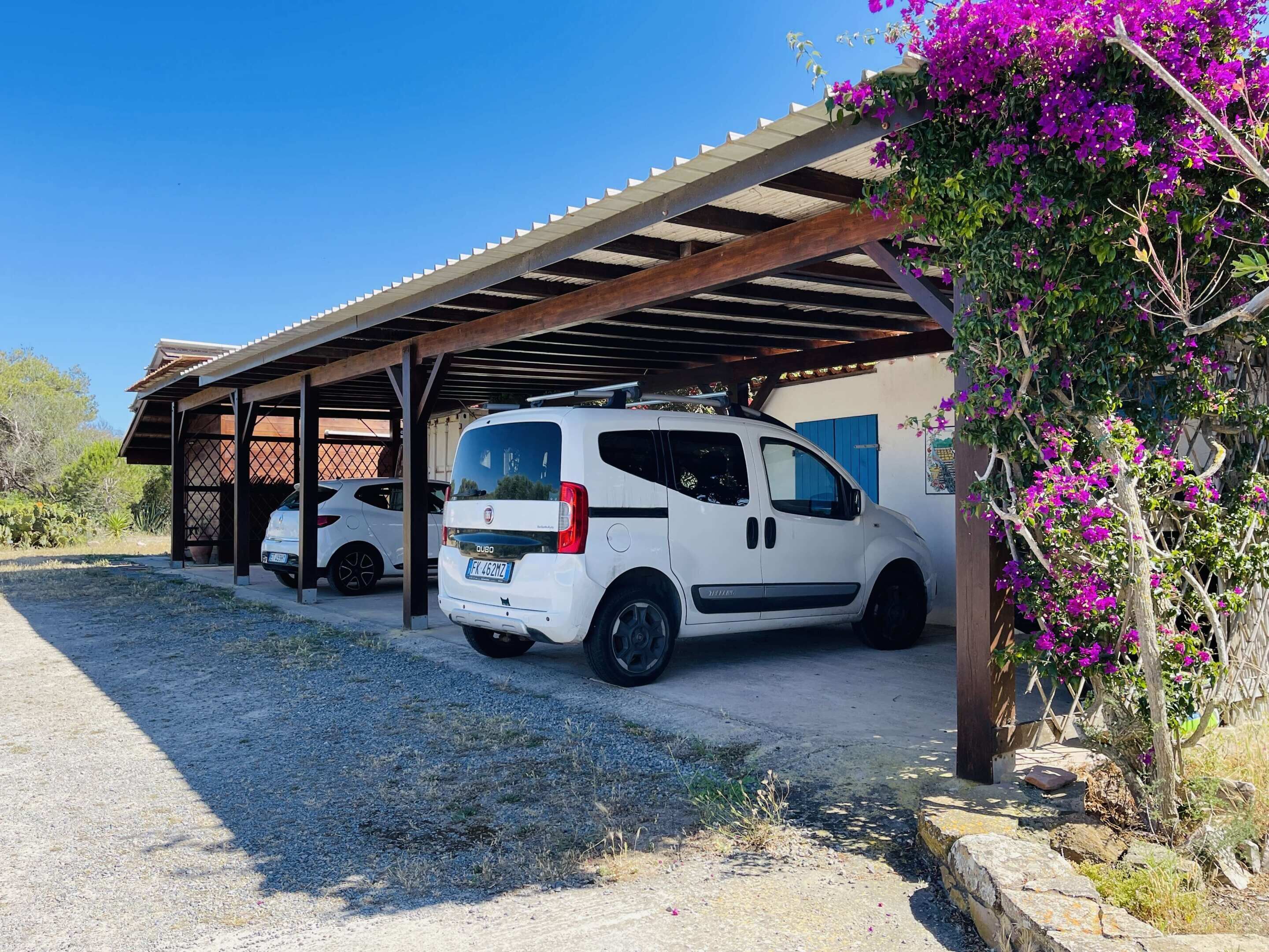 A white van parked under a covered area with a gravel driveway.