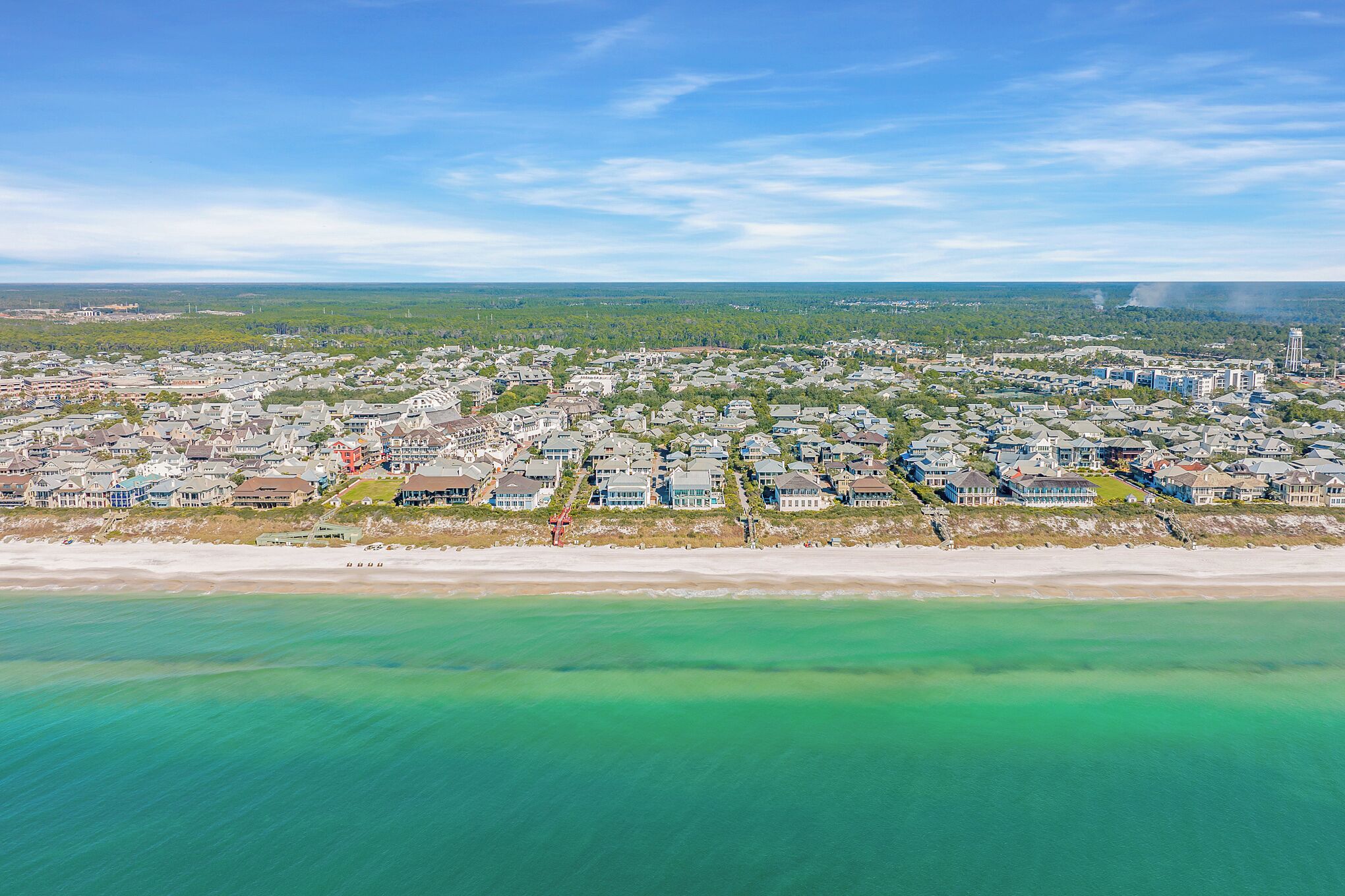 Vista aérea de un pueblo costero con edificios residenciales, una playa y cielo despejado.