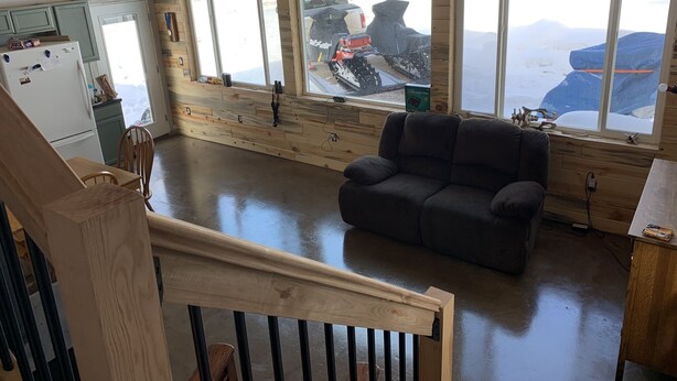 A spacious room with a large window overlooking a snowy landscape, a wooden floor, and a gray sofa. - Big Hole Valley cabin near river access (Wise River)