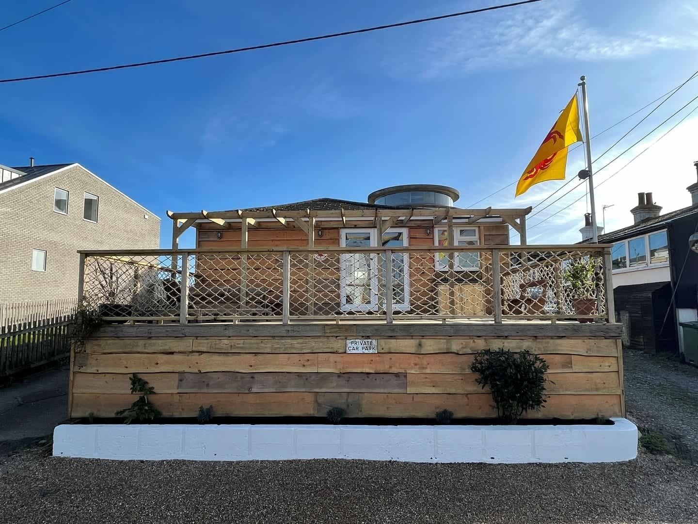 Un bâtiment à deux étages doté d’une terrasse en bois et d’un drapeau.