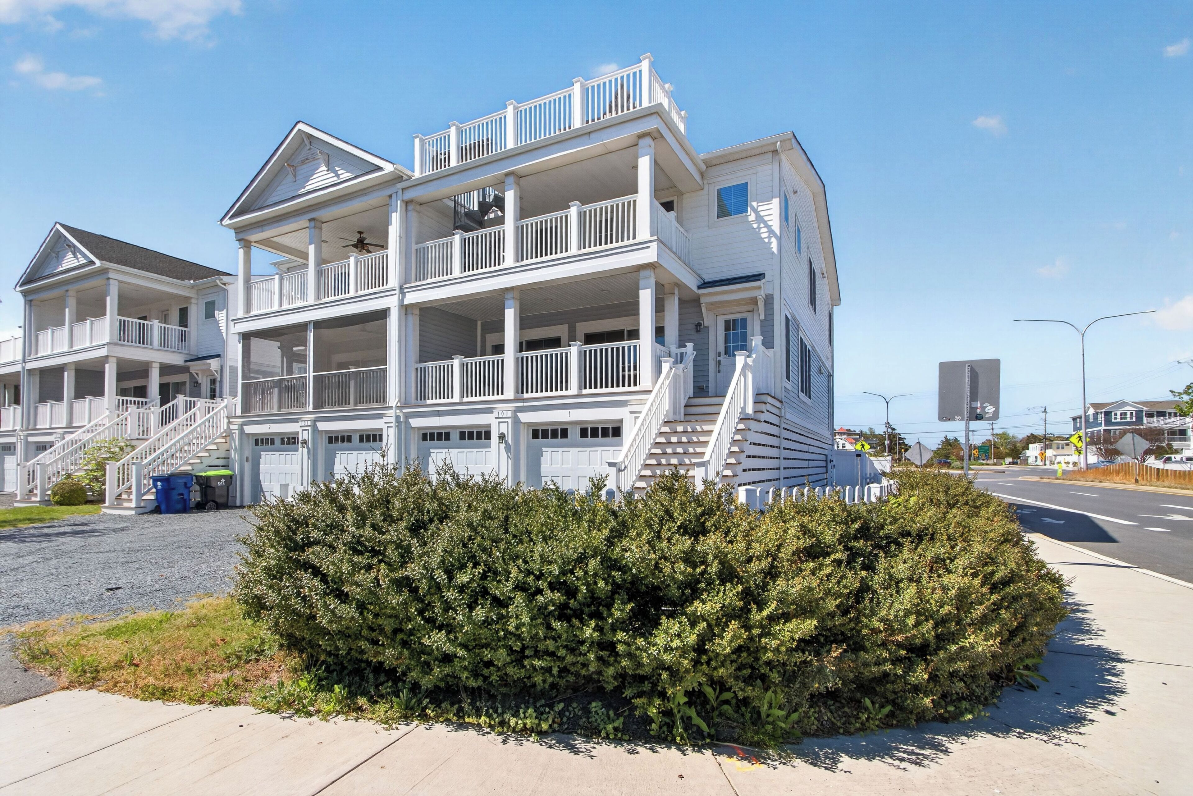 Une maison à plusieurs étages située en bord de mer, dotée de balcons, d’un porche abrité et d’un garage.