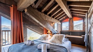 Une chambre confortable avec un grand lit, des poutres en bois et une vue sur les montagnes.