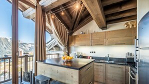 Une cuisine moderne avec des meubles en bois, un îlot central décoré de fruits et une vue sur les montagnes.