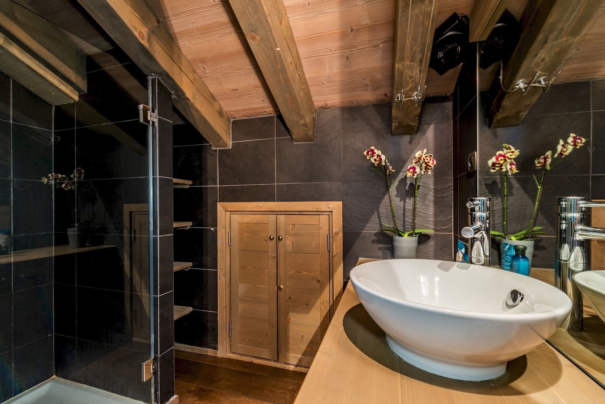Une salle de bain moderne avec une baignoire sur pieds, une porte en bois et des murs carrelés.
