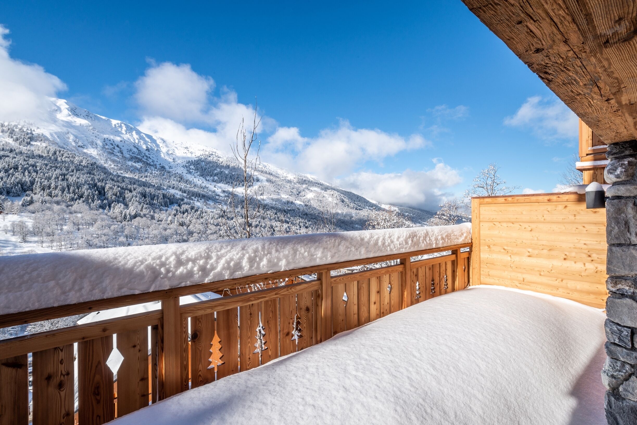 Un balcon en bois donnant sur un paysage enneigé et offrant une vue sur des montagnes recouvertes de neige.