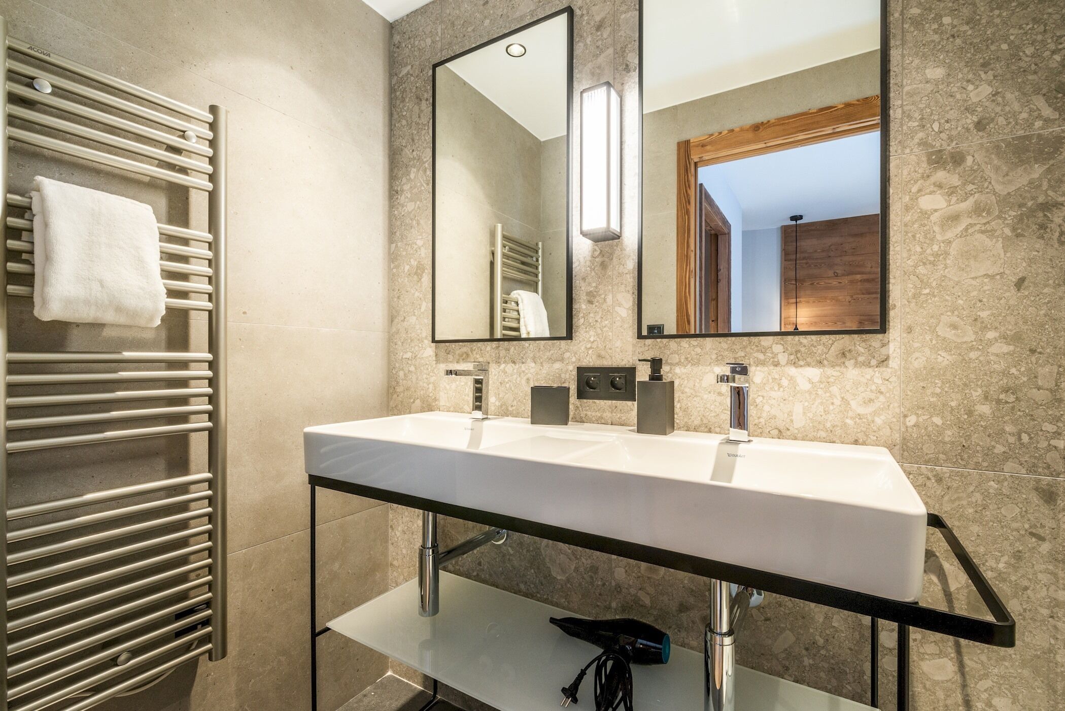 Une salle de bain moderne avec un grand miroir, un lavabo blanc et un porte-serviettes.