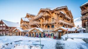 A wooden chalet-style hotel with multiple balconies and a ski shop.