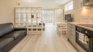 A modern kitchen with a dining area, a sofa, and a white partition. - Pass the Keys | Flat 9 Lovell Lodge - Modern Studio near Science Park (Cambridge)