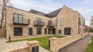 A modern brick building with a flat roof, multiple balconies, and a well-maintained lawn. - Pass the Keys | Flat 9 Lovell Lodge - Modern Studio near Science Park (Cambridge)