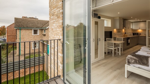 A modern apartment with a balcony, a glass shower enclosure, a kitchen with white cabinets, and a dining area. - Pass the Keys | Flat 9 Lovell Lodge - Modern Studio near Science Park (Cambridge)