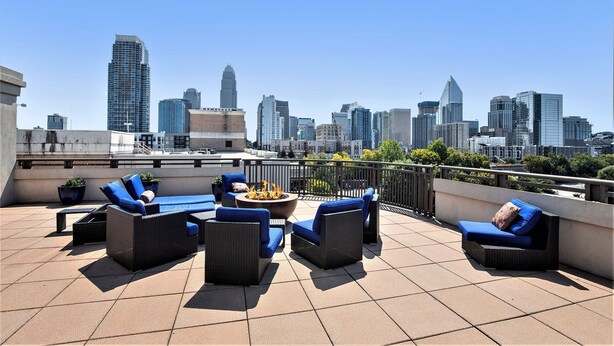 Una terraza en la azotea con asientos al aire libre, una chimenea y vistas al horizonte de la ciudad.