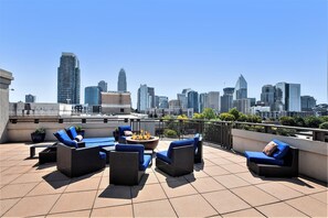 A rooftop terrace with outdoor seating, a fire pit, and a city skyline view. - A Modern Boho, Uptown  2 bdrm Condo + Rooftop  Terrace (Charlotte)