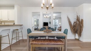 Un comedor con una mesa de madera, seis sillas, un banco y una araña.