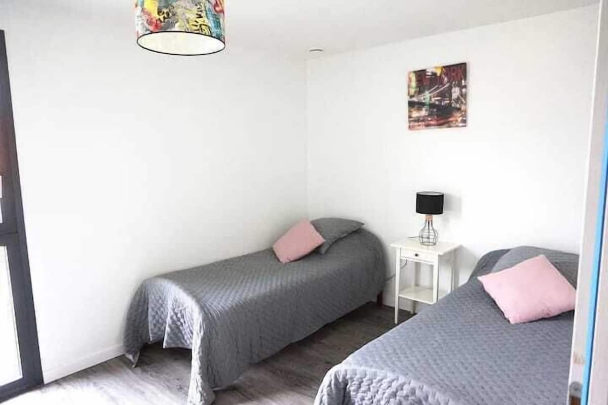 Un dormitorio con dos camas, una mesita de noche, una lámpara y un cuadro en la pared.