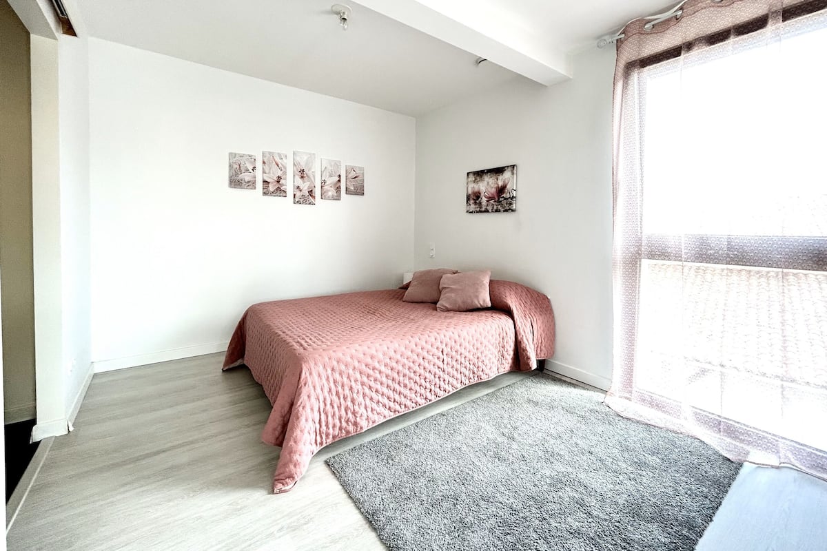 Un dormitorio con una cama, una alfombra gris y cuadros en la pared.