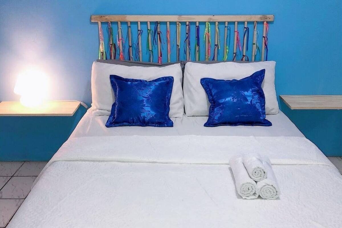 A bed with white bedding, two blue pillows, and a neatly folded white towel.
