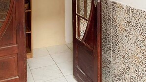 A wooden door with glass panels, a tiled floor, and a wall with various signs. - Oxe Rooms (Salvador)