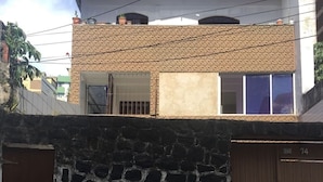 A two-story building with a stone wall and a brown gate. - Oxe Rooms (Salvador)