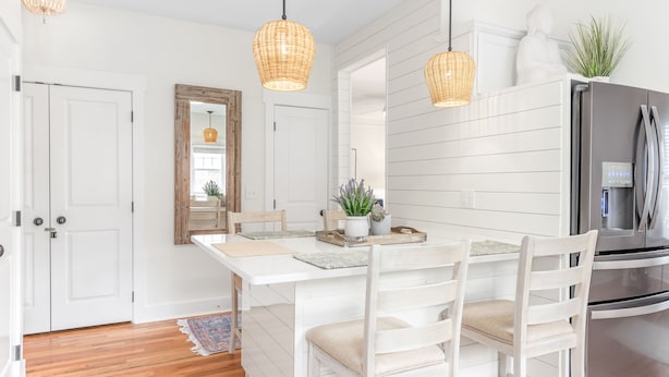 Una cocina con armarios blancos, un refrigerador de acero inoxidable y una mesa de comedor con sillas.