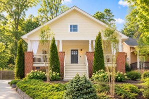 A two-story house with a front porch, a brick chimney, and a well-maintained garden.