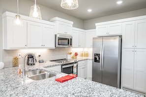 A modern kitchen with white cabinets, stainless steel appliances, granite countertops, and pendant lighting. - Close to everything, New Fayetteville Home! (Fayetteville)
