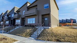 A modern multi-story residential building with a flat roof, large windows, and a staircase leading to the entrance. - Close to everything, New Fayetteville Home! (Fayetteville)