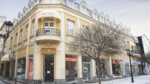 Un hotel de estilo arquitectónico europeo clásico, con un balcón prominente y un cartel que indica que se encuentra en el centro de la ciudad de Plovdiv.