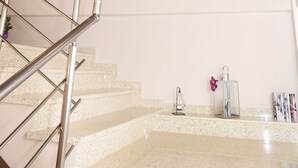Una escalera con barandilla de metal, una ventana con luz natural y obras de arte en la pared.
