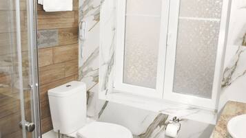 A bathroom with a glass shower enclosure, a toilet, a bathtub, and a marble wall.