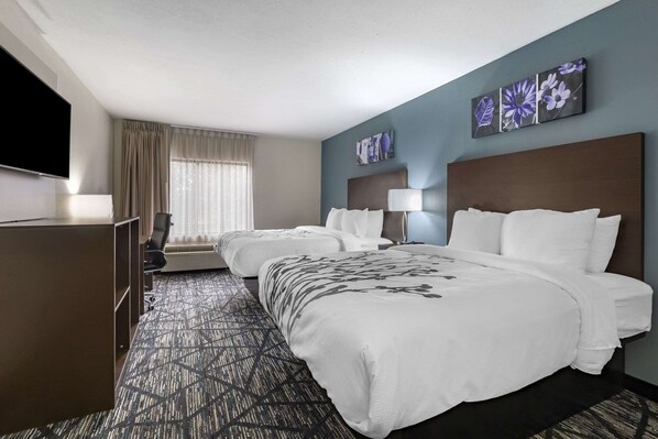 Une chambre d’hôtel avec un grand lit, un lit plus petit, un bureau et une télévision.