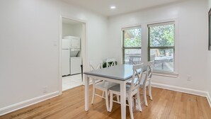 Un comedor con mesa y sillas, una cocina al fondo y una ventana con persianas.