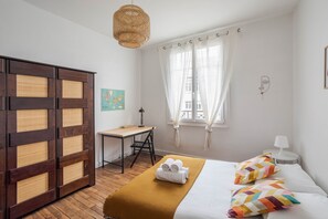A hotel room with a bed, a desk, a wardrobe, and a window with curtains.