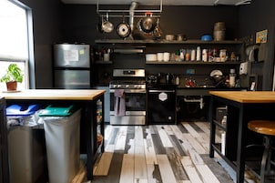 A compact kitchen with stainless steel appliances, a tiled backsplash, and a wooden countertop.