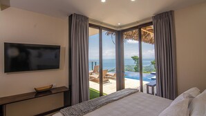 Un dormitorio con cama, televisor y vistas a una piscina exterior y paisaje.
