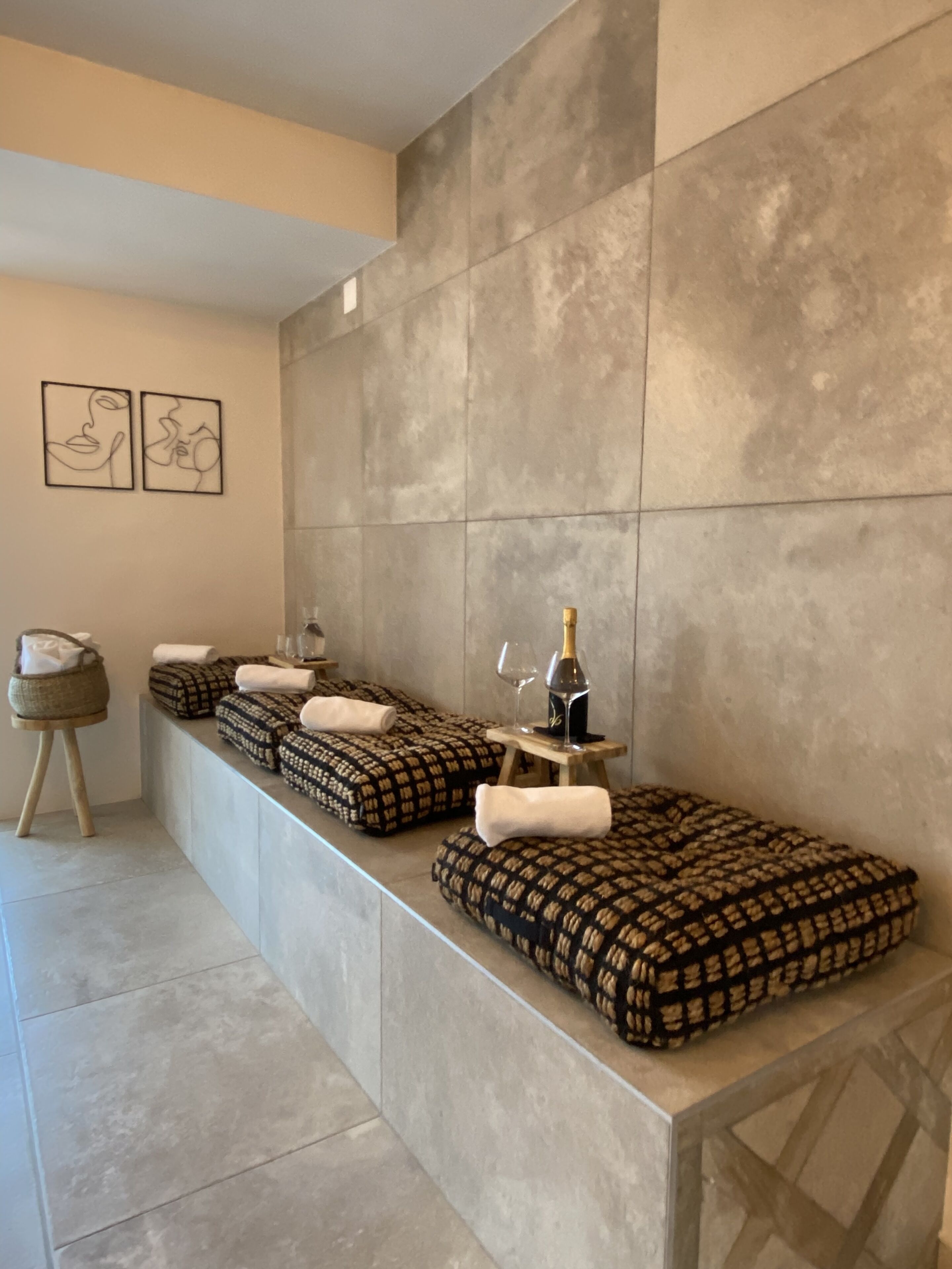 A modern bathroom with a large mirror, a towel rack, and a small table with a bottle and glass.