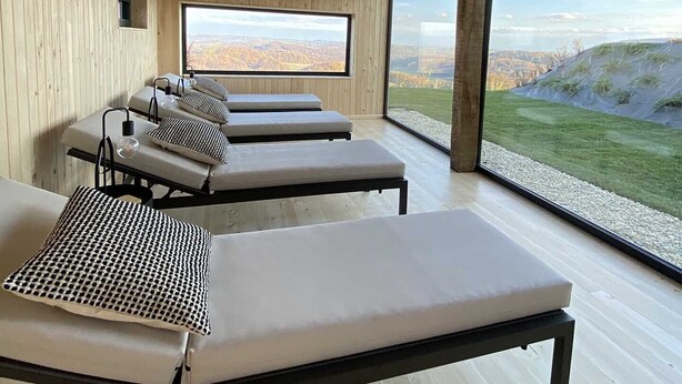 A wooden interior with four sunbeds and a large window overlooking a landscape. - SIBON Wine & Spa Resort Jeruzalem (Ljutomer)